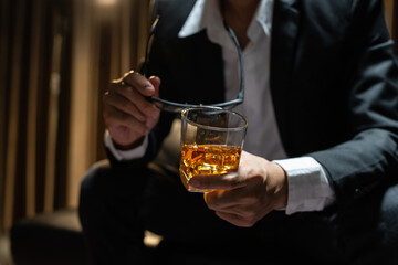 Businessman sitting Holding a Glass of Whiskey Drink Whiskey in the liquor store room