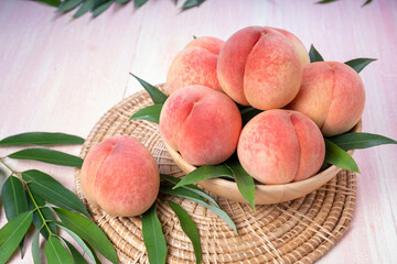 Pink Peach on wooden basket, White Peach with leaf on pink wooden background.