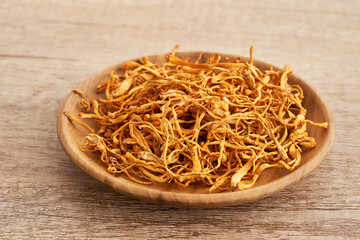 dry cordyceps militaris mushroom in wood plate on table background. pile of dry cordyceps militaris mushroom. dry cordyceps militaris mushroom food background                       