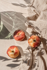 Ripe peach fruits on neutral beige tabletop, linen tablecloth, aesthetic floral sunlight shadow....