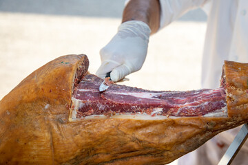 Professional man hands chef slicing iberico spanish pork cured ham in restaurant event party table