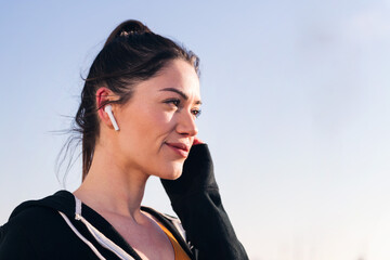 close up portrait of a beauty sportswoman using earphones outdoors in a sunny day, concept of...