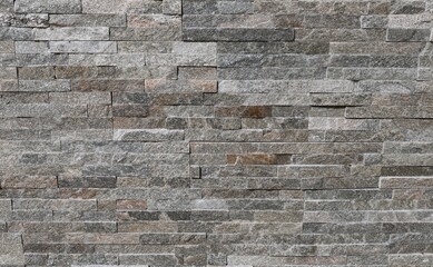 Stone cladding wall made of striped stacked bricks of multicolor rocks. Panels for exterior, background and texture.