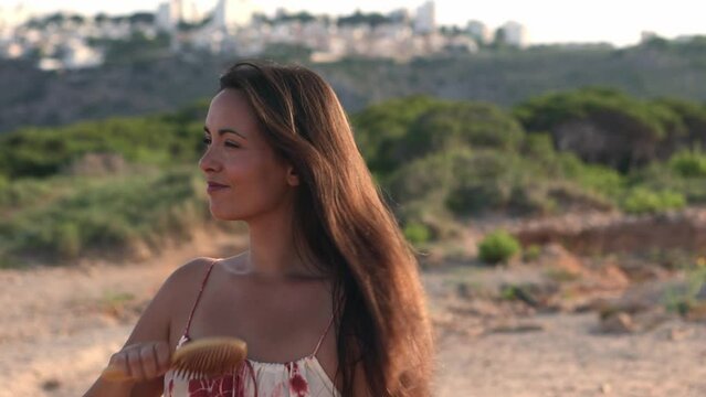 young woman combing her long  hair in nature