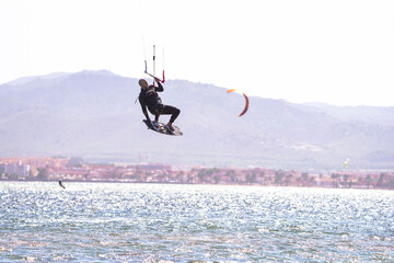 Sportsman practices kitesurf at the Spanish coasts doing a trick
