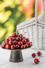 Fruits and berries. Summer time. Delicious fresh cherries on a stylish iron tray in retro style on a white table. Space for text.