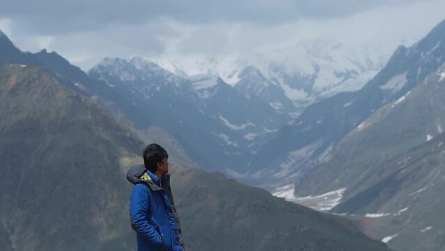 Portrait of Indian man looking at snow covered mountains at Rohtang pass, Manali, India.  People enjoying vacation. Winter background for travel.