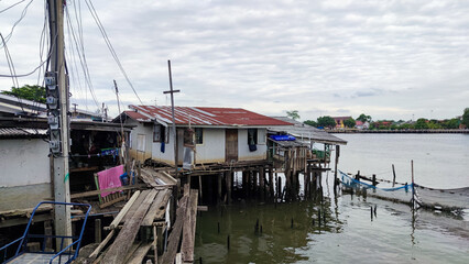 Dangerous wooden bridge over the river in slums with small house