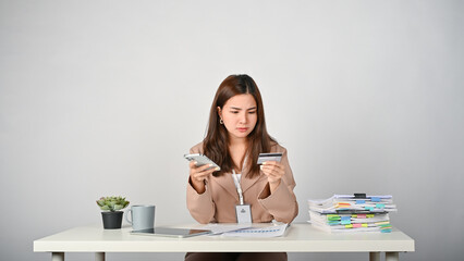 Young Asian businesswoman feeling upset while holding credit card