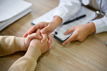Close up view of doctor touching patient hand, showing empty and kindness.