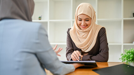 A beautiful Asian Muslim businesswoman is in the meeting with her financial consultant