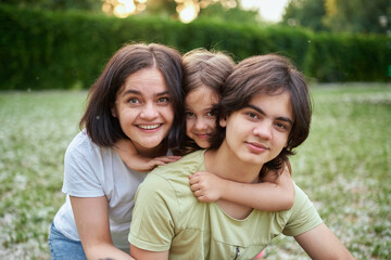 Fototapeta premium Young adult caucasian beautiful mother enjoy having fun with two cute children outdoors on warm summer day. Family nature outdoor recreation lifestyle. High quality photo