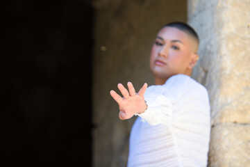 Non binary latin and young person, he is in a castle making different body expressions and approaches his hand to the camera. Concept of diversity, homosexuality and gay pride.