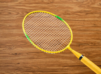 Yellow colorful badminton racket on a wooden background. Concept of sport play