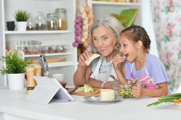 Portrait of senior woman with granddaughter preparing dinner