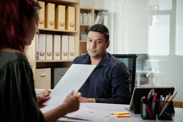 Entrepreneur listening to colleague analyzing data from report