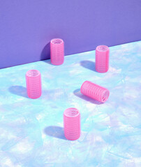 Lots of pink hair curlers scattered on a blue surface. The idea of beauty, creating stylish hairstyles, fashion and trends.