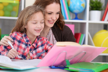 Cute little girl with her mother doing homework
