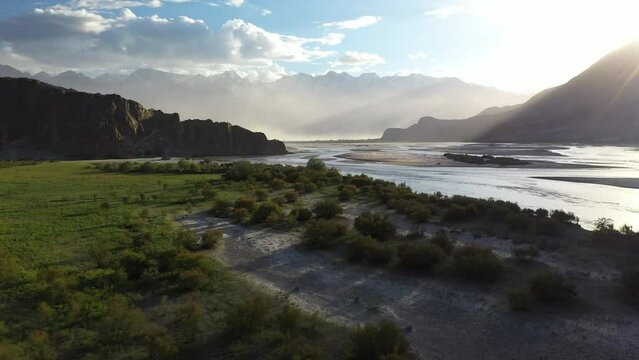 Drone footage, Skardu Valley located in Gilgit-Baltistan, Pakistan. Flying low, into the sun and over the river, aerial shot. Confluence of the Shigar River and Indus River.