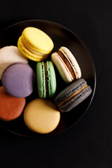 Colorful macaron cookies on black color plate. Sweet and colorful French macarons.