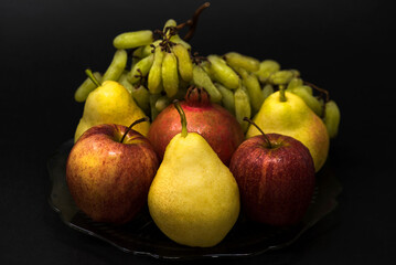 Fruits, apples, grapes, pears, pomegranate on black background