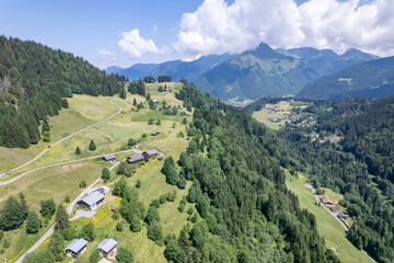 Mountain slope French Alps village Les Gets seen from above with high peaks in the background. Aerial of ski area mountainous winter sports region during summer.