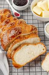 Homemade challah bread with sesame seeds, butter and jam on a grey concrete background. Sweet...