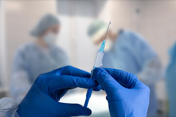 Close up man doctor holding syringe. Doctor in surgical mask and gloves preparing syringe for injection.