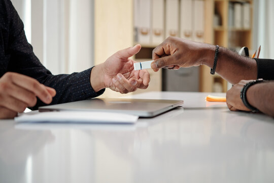 Hands of developer giving USB flash drive with importtant data to colleague