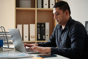 Serious businessman working on laptop at his office desk