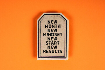 NEW MONTH MINDSET START RESULTS concept. Cardboard sticker with text on an orange background