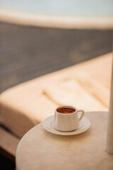 Cup of hot coffee on table by the blue pool on a sunny summer day. cozy warm mood, brown tones. Black coffee in traditional Turkish cup. turkish coffee