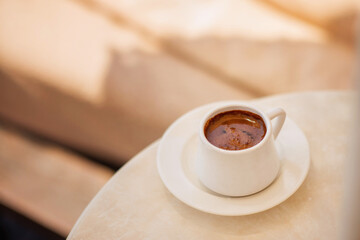 Cup of hot coffee on table by the blue pool on a sunny summer day. cozy warm mood, brown tones. Black coffee in traditional Turkish cup. turkish coffee