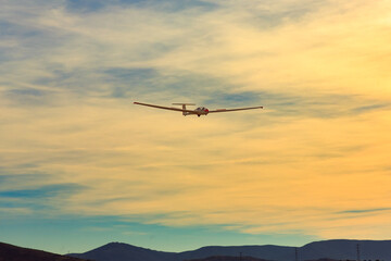Fototapeta na wymiar Glider approach for landing against the backdrop of mountains at sunset.