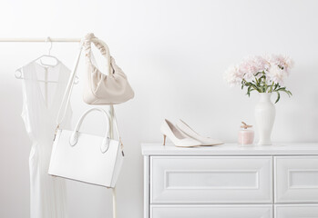 white dresser with clothes and flowers in white room