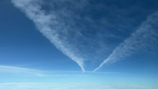 Aerial view from a jet cabin of two wake trails vanishing. 10000m high.