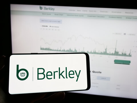 Stuttgart, Germany - 06-24-2023: Person holding mobile phone with logo of US insurance company W.R. Berkley Corporation on screen in front of web page. Focus on phone display.
