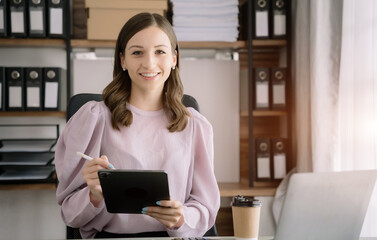 Female asian sitting at the desk, looking to camera.