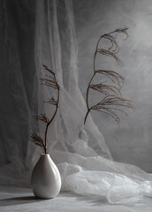Modern still life with dry branches against a background of flowing fabric