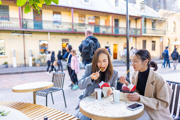 Happy Asian woman friends having lunch at outdoor restaurant during shopping together in the city....