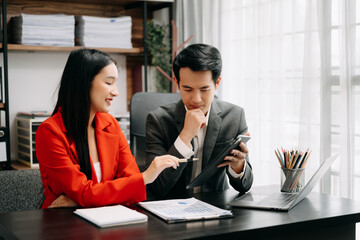 Asian business colleague business presents and explains and using laptop and tablet. Teamwork, financial marketing team,   while sitting in office room.