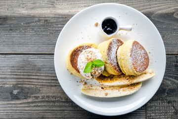 pancakes with chocolate and banana and whip cream on top in plate on wooden table, delicious dessert for breakfast.