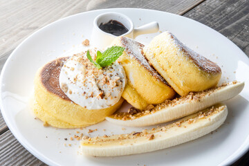 pancakes with chocolate and banana and whip cream on top in plate on wooden table, delicious dessert for breakfast.
