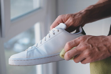  A man cleans white sneakers from dirt