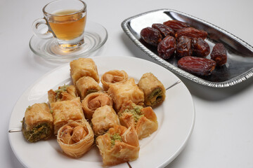 Layered stuffed pastry Baklava middle eastern sweet dessert dry ripe sweet date fruit tea in transparent glass cup saucer on white background