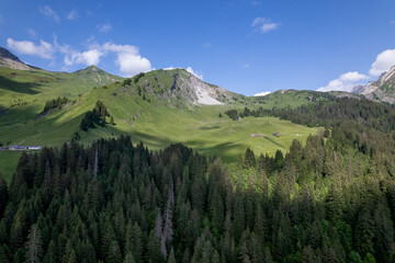 French mountainous Morzine village with impressive rock formations rising above the pine tree forest. Aerial natural beauty