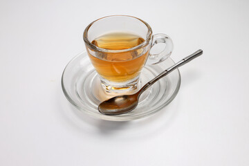 Hot tea in transparent glass cup saucer on white background