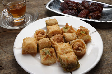 Layered stuffed pastry Baklava middle eastern sweet dessert dry ripe sweet date fruit tea in transparent glass cup saucer on rustic wooden background