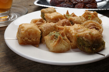 Layered stuffed pastry Baklava middle eastern sweet dessert dry ripe sweet date fruit tea in transparent glass cup saucer on rustic wooden background