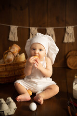 A child under one year old in a chef's outfit on a brown background with props for baking